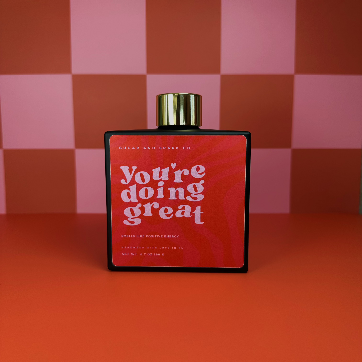 Red bottle with gold cap on a checkered background